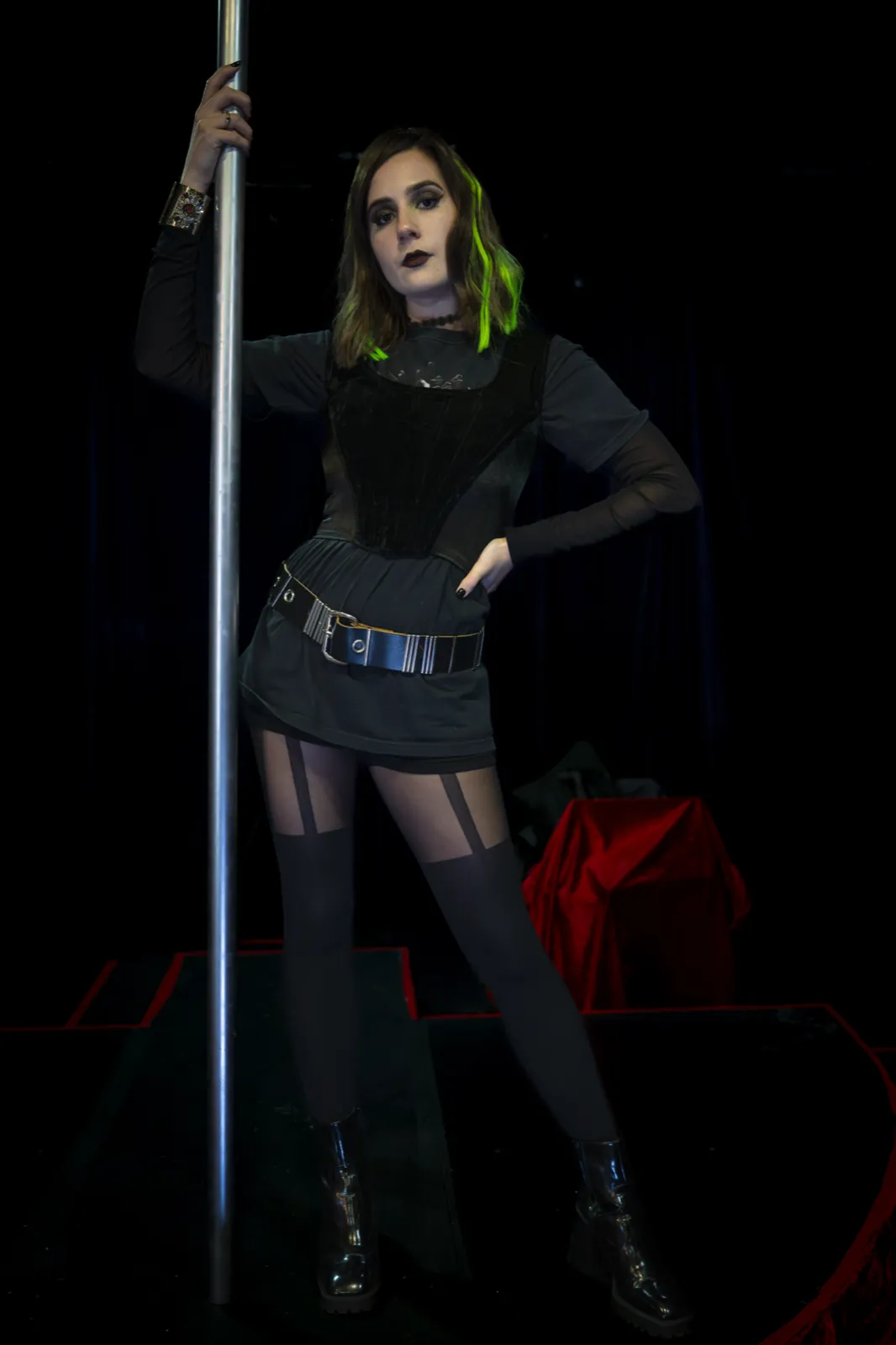 A dancer with green hair extensions at the pole on the club stage